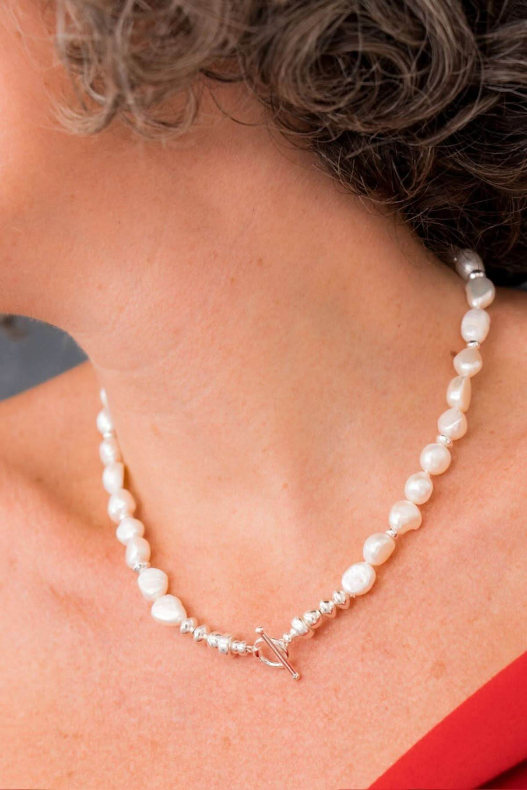 Collier élégant en perles d'eau douce, porté avec un fermoir en T pour un style sophistiqué.