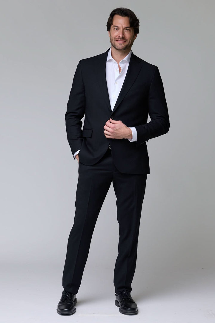 Homme portant un complet classique deux pièces noir élégant pour occasions formelles.