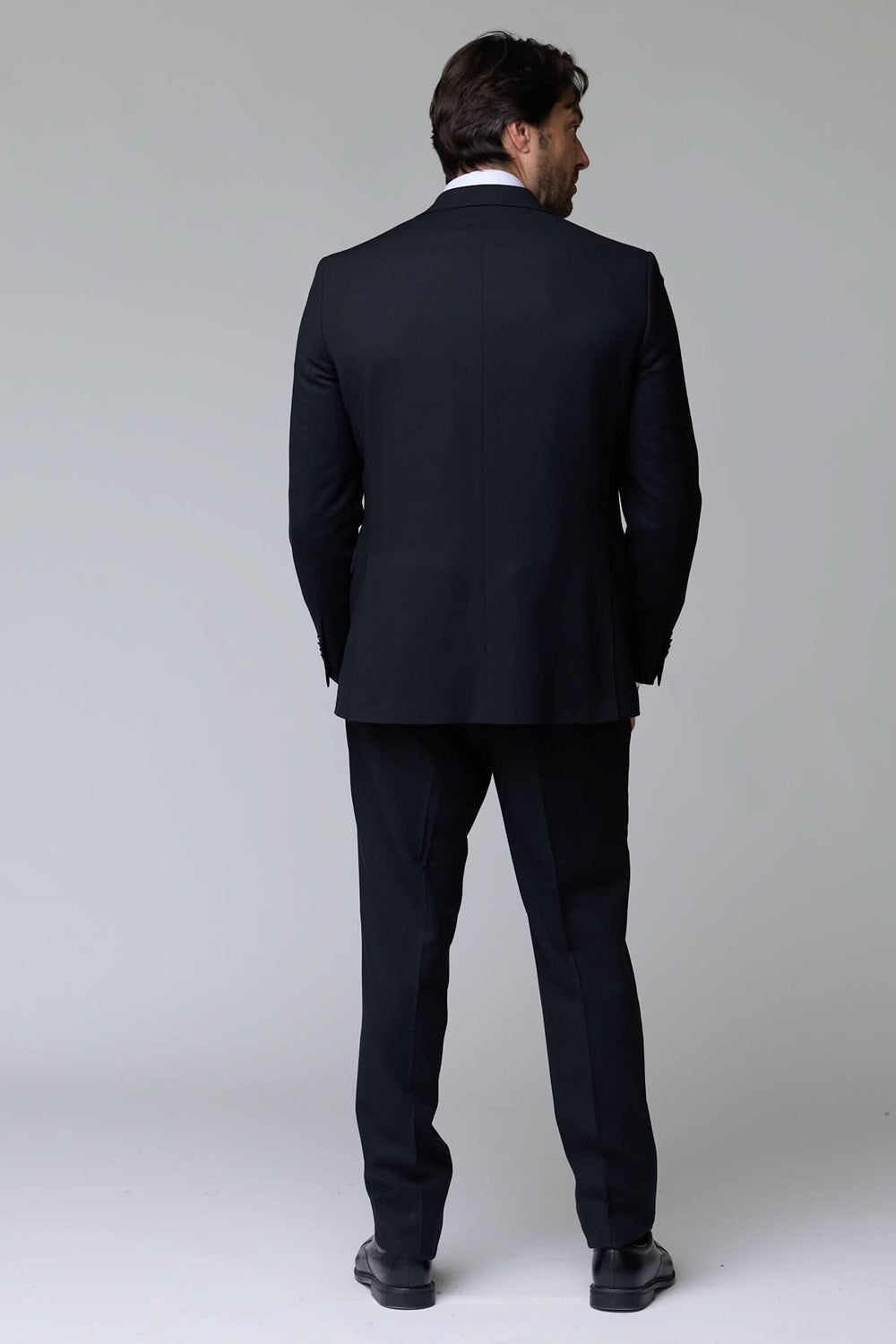 Homme portant un complet classique deux pièces noir, vue de dos