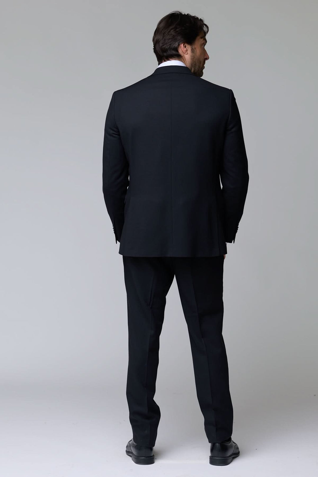 Homme portant un complet classique deux pièces noir, vue de dos