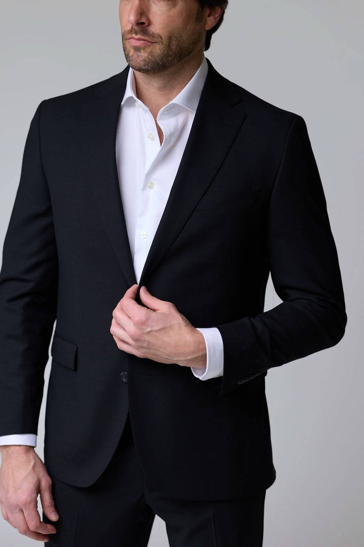 Homme portant un complet classique deux pièces noir, élégant et raffiné pour événements formels.