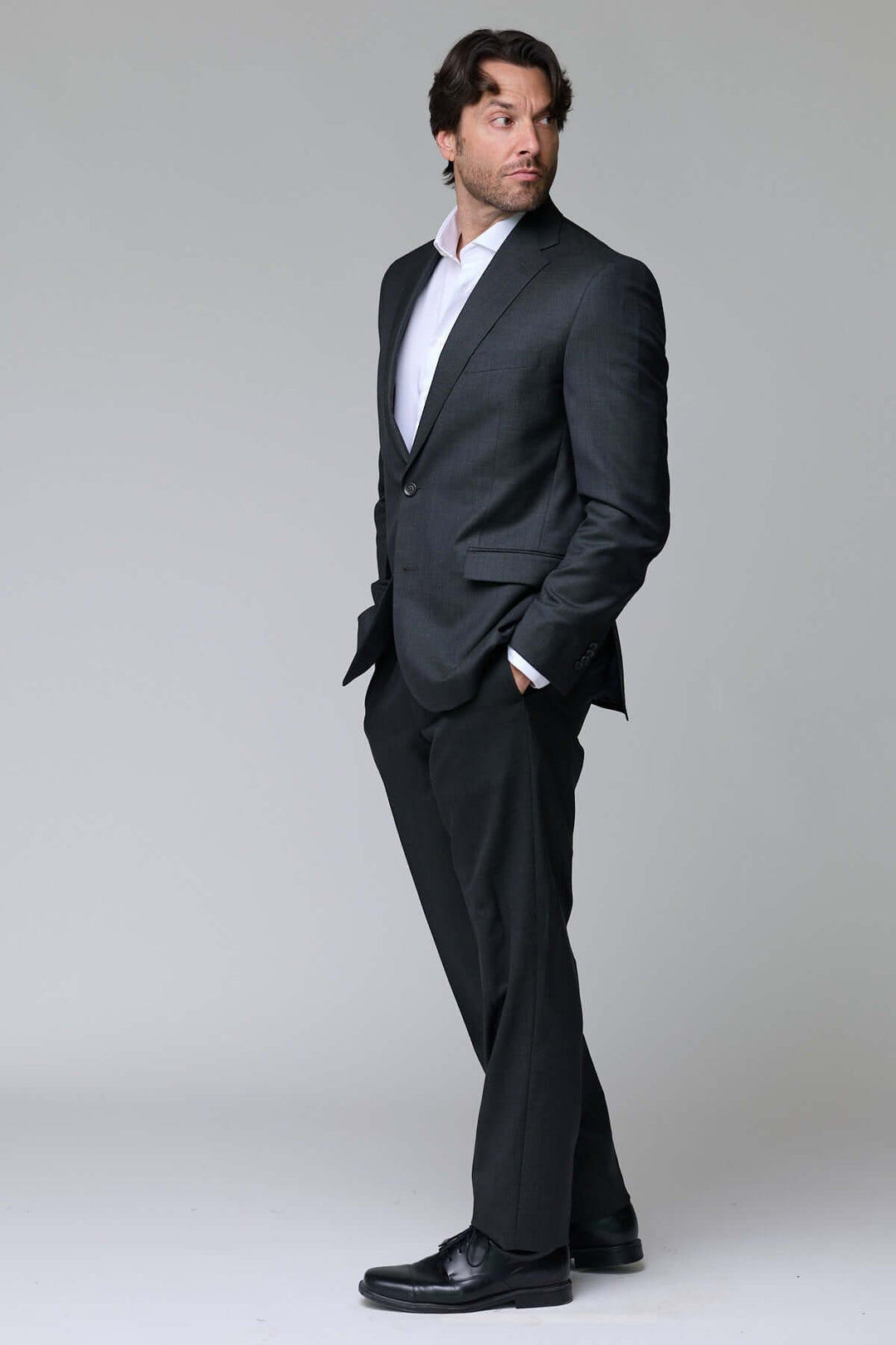 Homme portant un complet classique deux pièces ajusté, idéal pour le bureau et les événements formels, en tissu fluide et structuré.