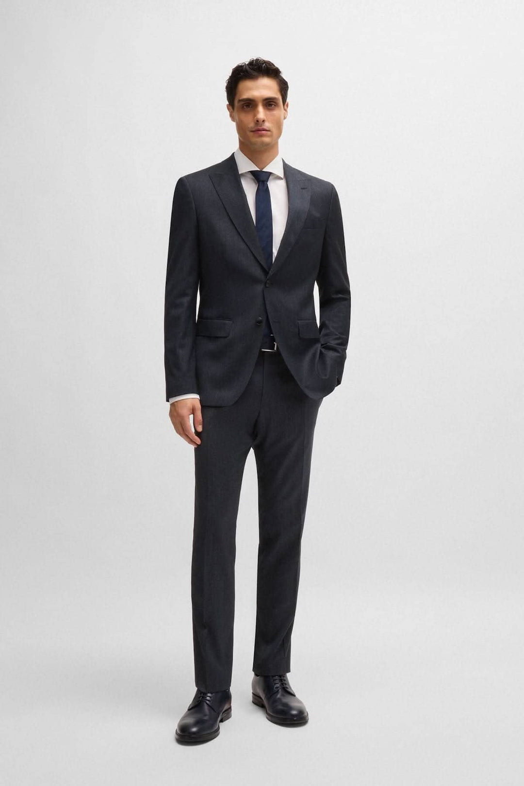 Homme en complet slim à micro-motifs, élégant et moderne, avec veste structurée et cravate.