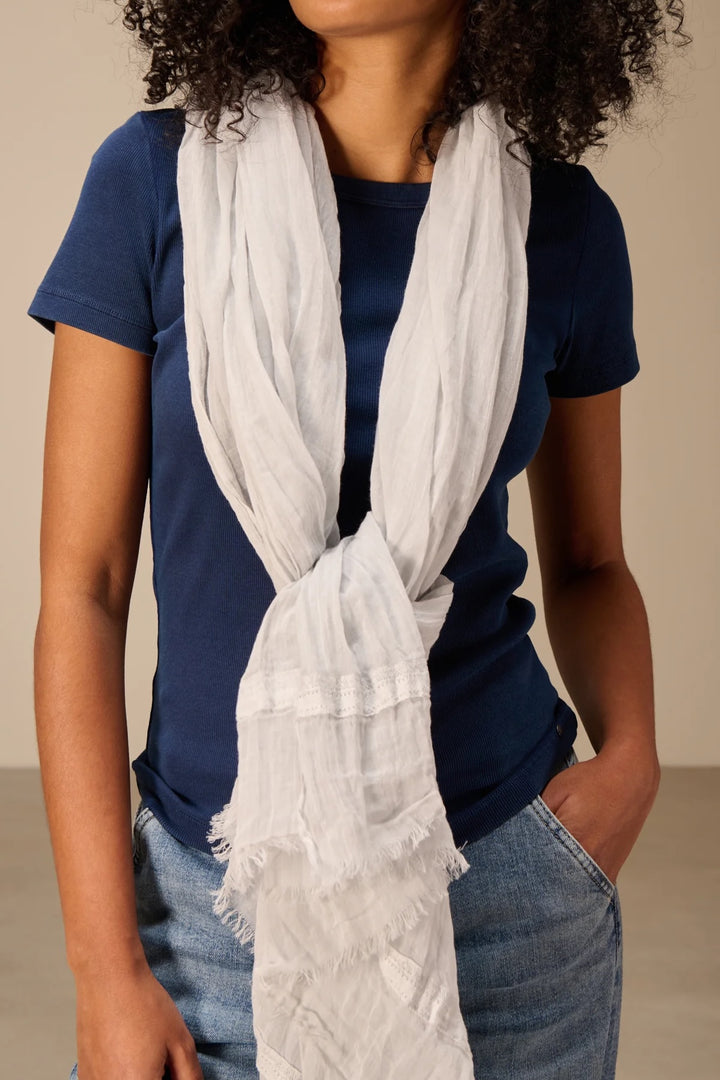 Foulard en coton léger porté autour du cou avec une finition délicate, parfait pour ajouter douceur et élégance à une tenue.