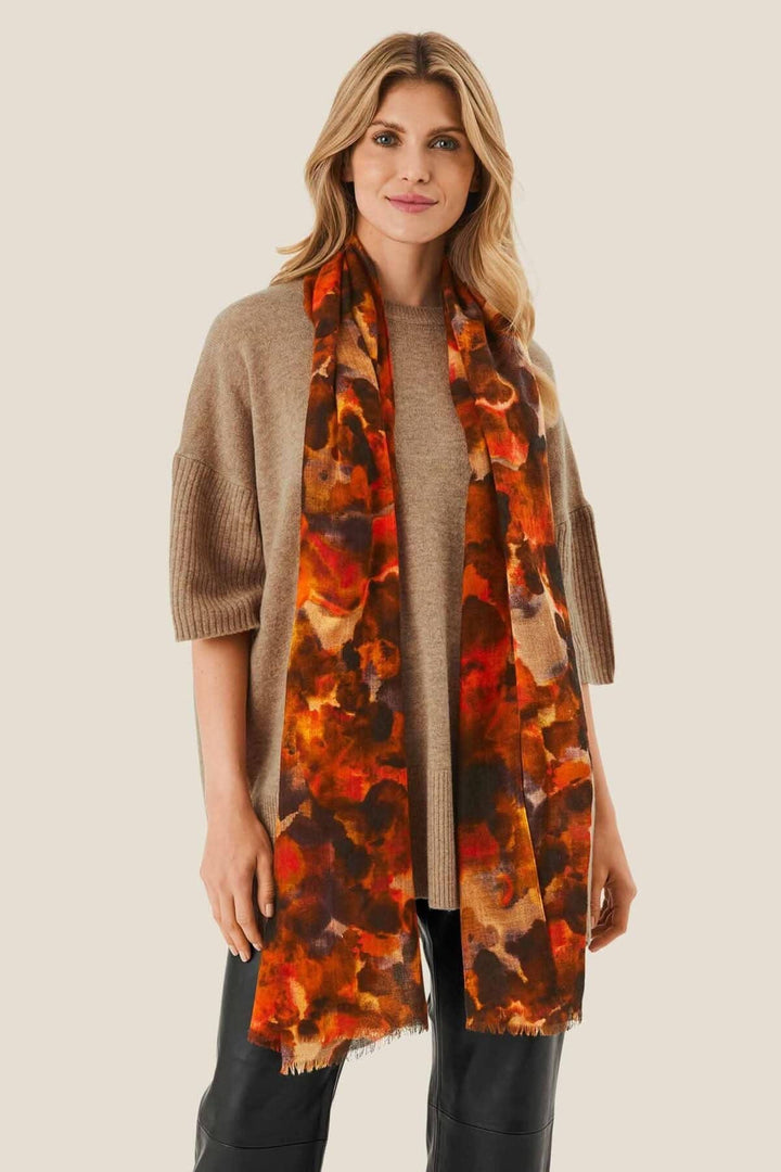Foulard Adama avec imprimé aux couleurs brûlées, léger en laine, porté de manière décontractée.