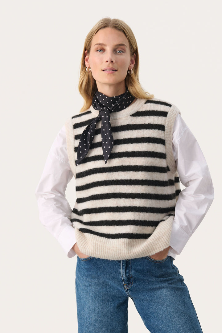 Foulard à pois noir et blanc porté avec un pull rayé, ajoutant une touche chic à un look décontracté.