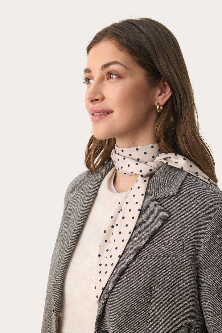 Foulard Lupa à pois porté par une femme, ajoutant une touche féminine et élégante à sa tenue.