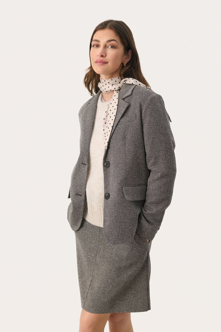 Foulard Lupa avec pois, associé à un blazer gris, offrant un look féminin et élégant.