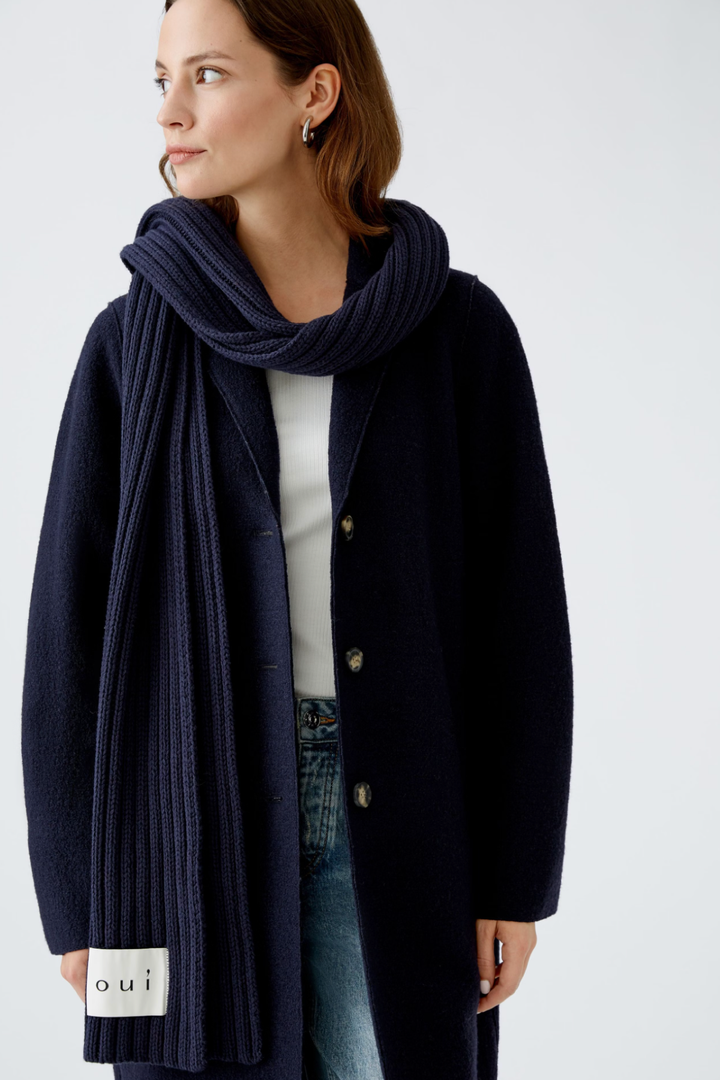 Foulard côtelé noir porté avec un manteau classique et un tee-shirt, style décontracté et moderne.