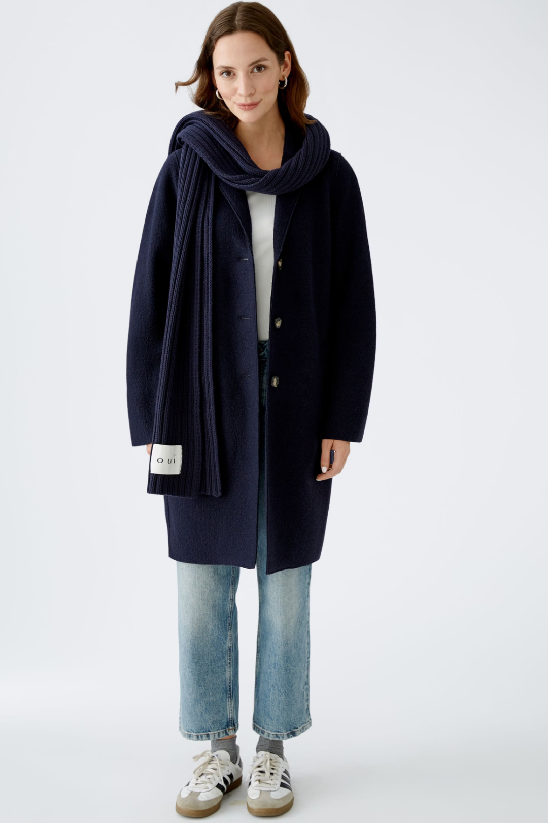 Foulard côtelé en tricot sportif porté avec un manteau classique et jeans décontractés, style moderne et tendance.