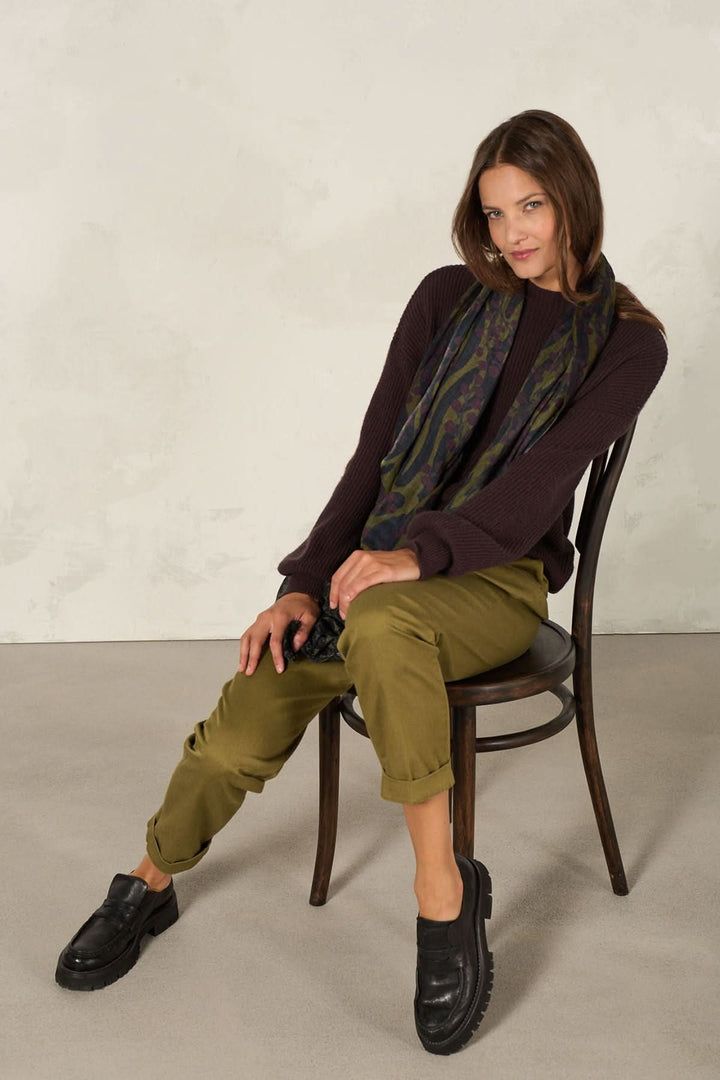 Foulard décoratif porté par une femme assise sur une chaise, style élégant et artistique.