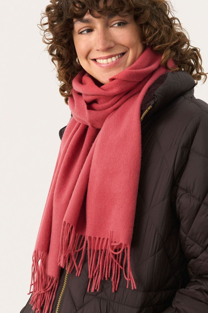 Foulard en laine Kitha en couleur rose porté par une femme souriante, parfait pour l'hiver.