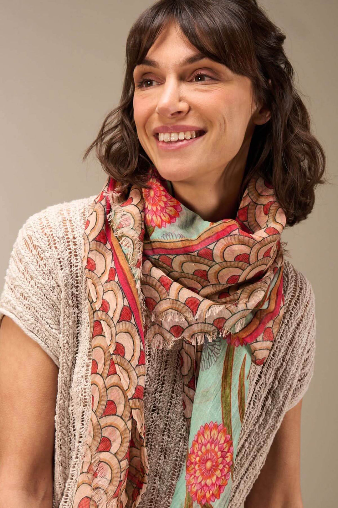 Foulard imprimé en coton bio, porté en écharpe par une femme, ajoutant une touche sophistiquée à sa tenue.