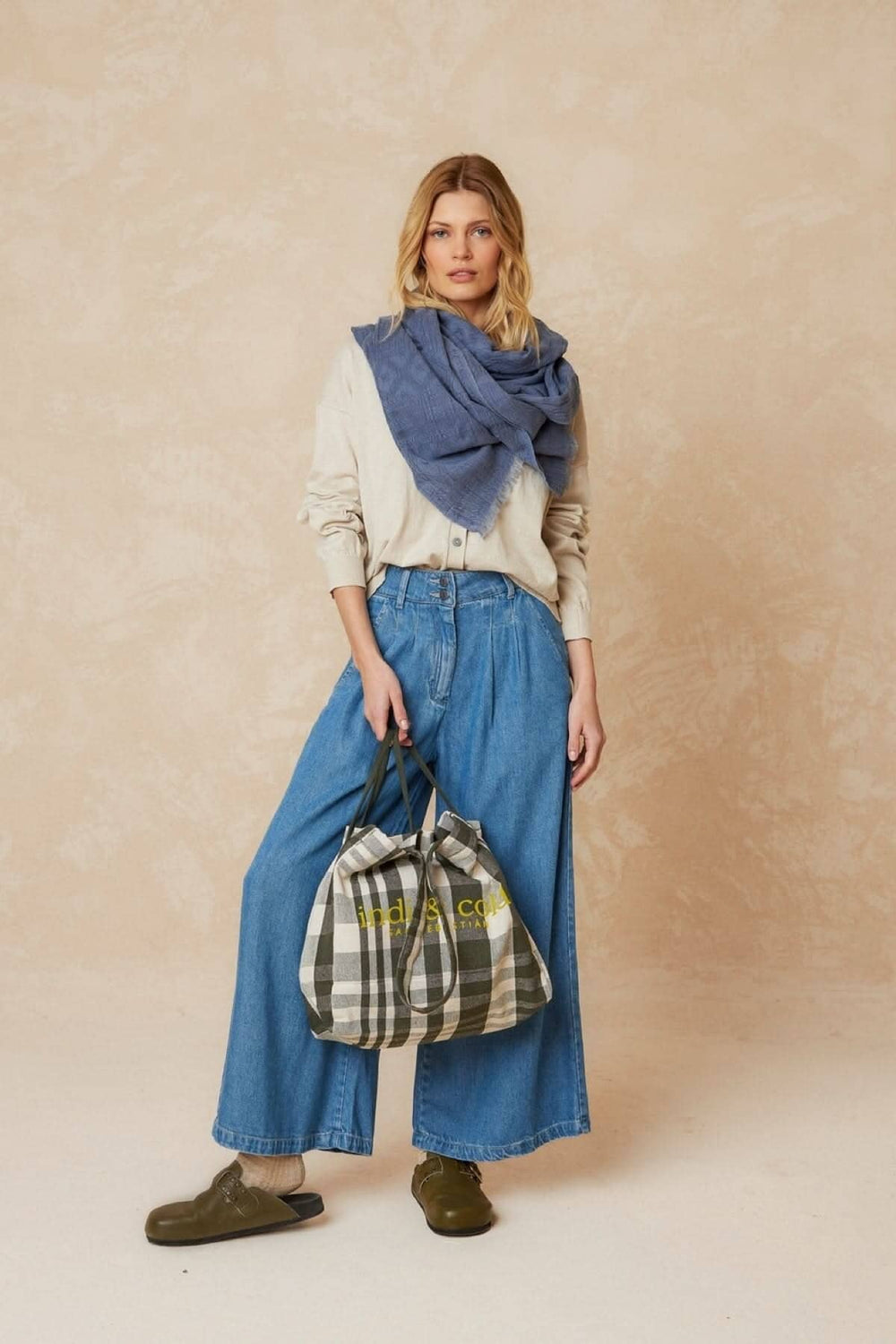 Foulard à motifs porté avec une tenue décontractée, sac à main à carreaux et jeans larges pour un look chic.