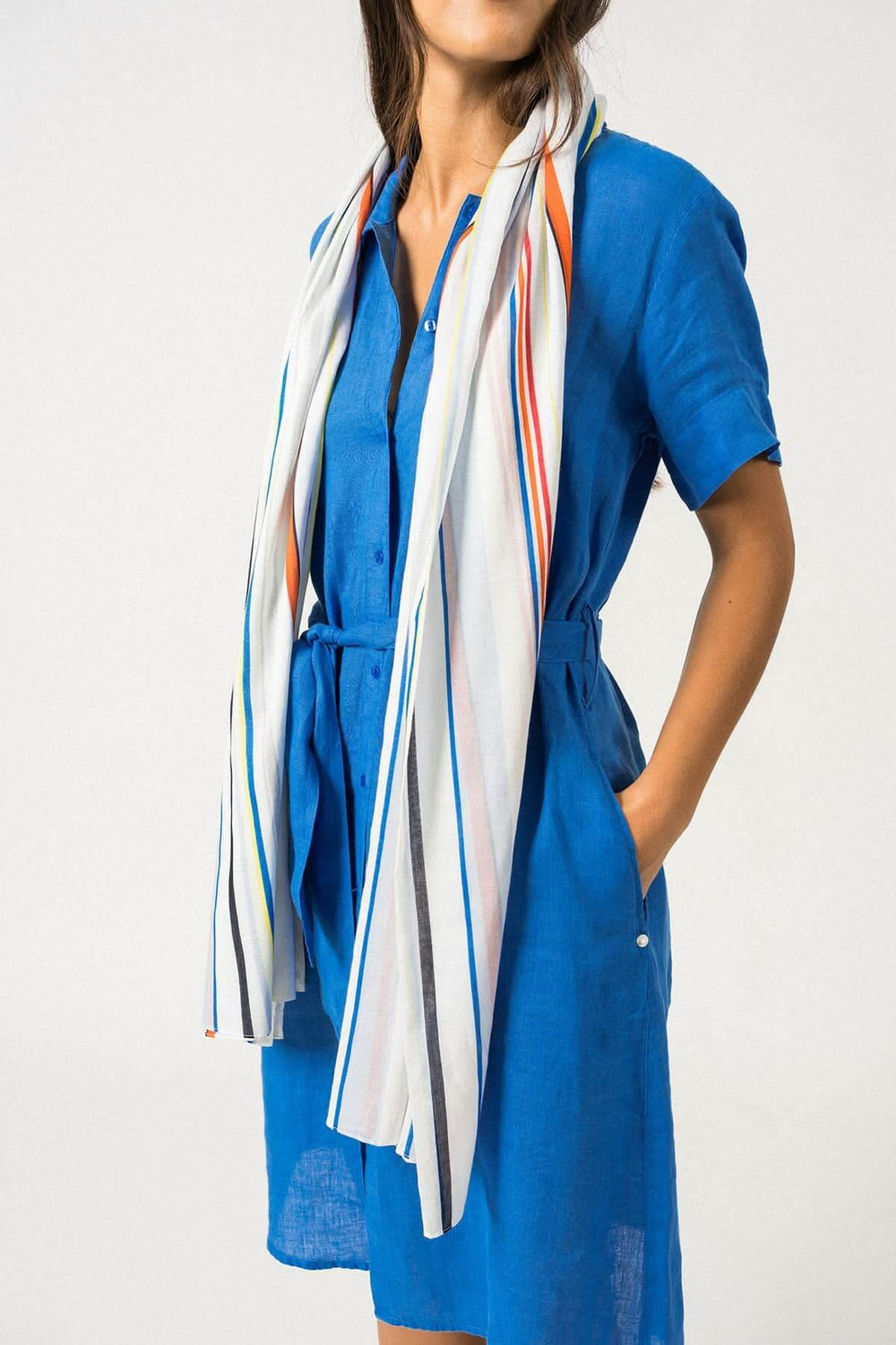 Foulard rayé coloré en coton porté sur une robe bleue, idéal pour la mi-saison, dimensions 68 x 180 cm.