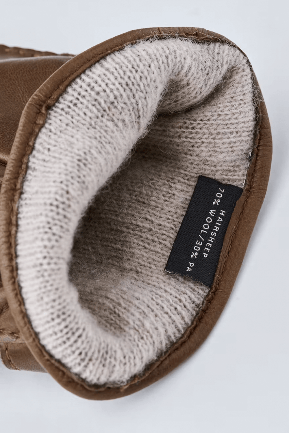 Intérieur des gants en cuir Jake, doublure en laine tricotée souple et étiquette de composition.