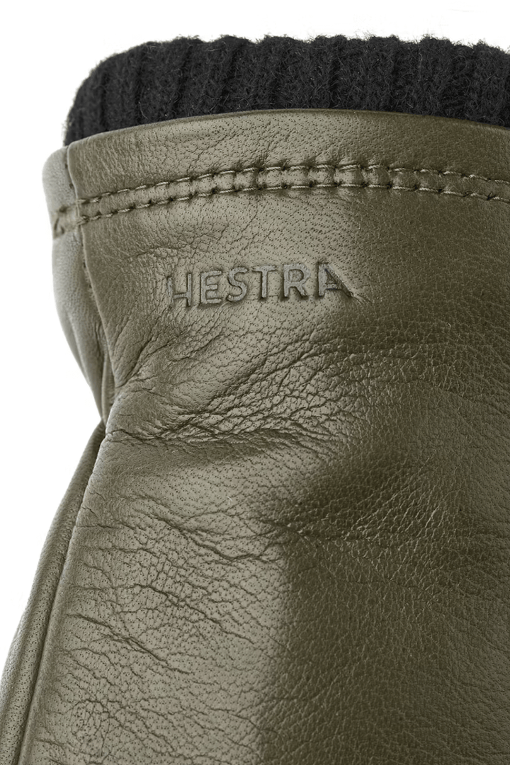Gants de cuir avec logo Hestra et poignets en laine côtelée, idéal pour l'hiver et les sorties en nature.