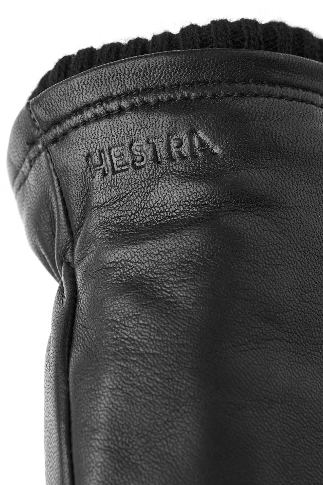 Détail d'un gant en cuir noir avec une finition en laine côtelée, portant le logo Hestra.