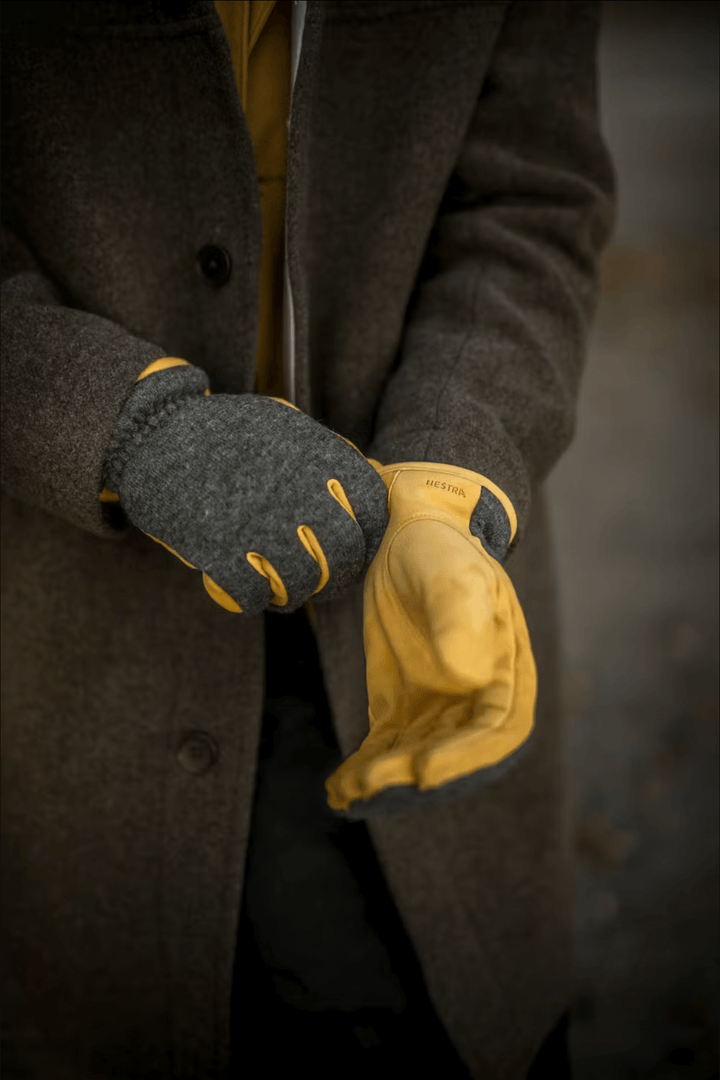 Homme portant des gants de cuir jaune et gris, parfaits pour un style décontracté en hiver.