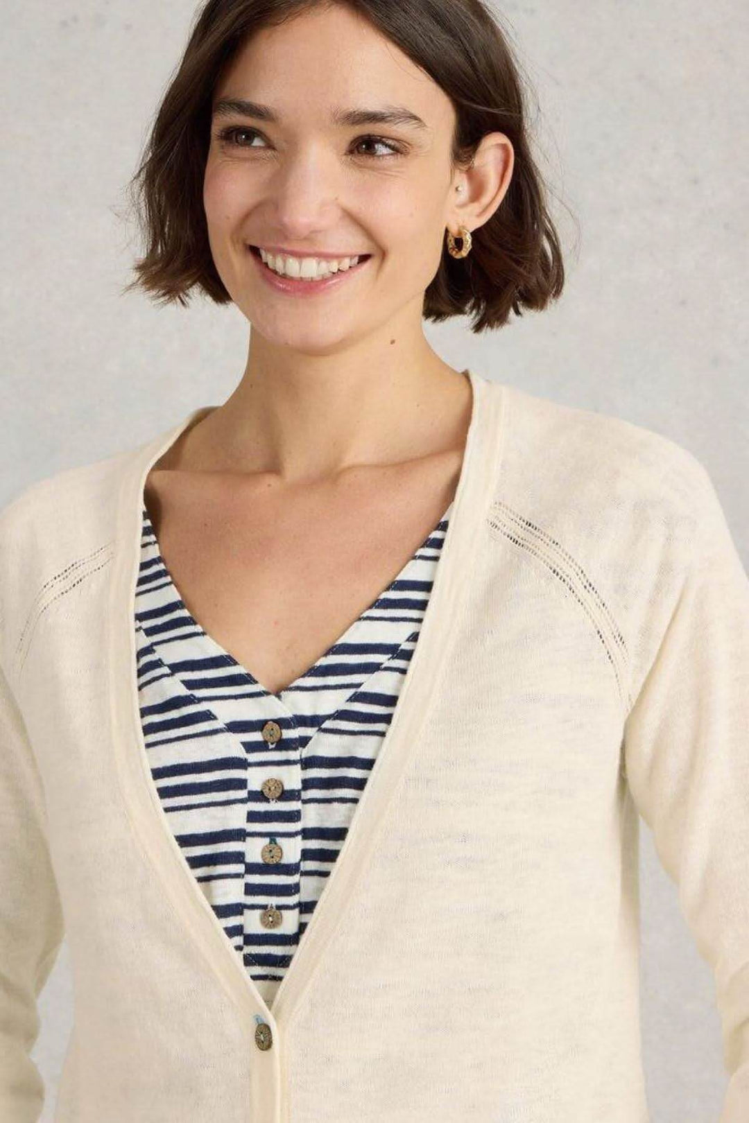 Gilet Col V Naria beige porté sur un haut rayé, dégageant une élégance décontractée.