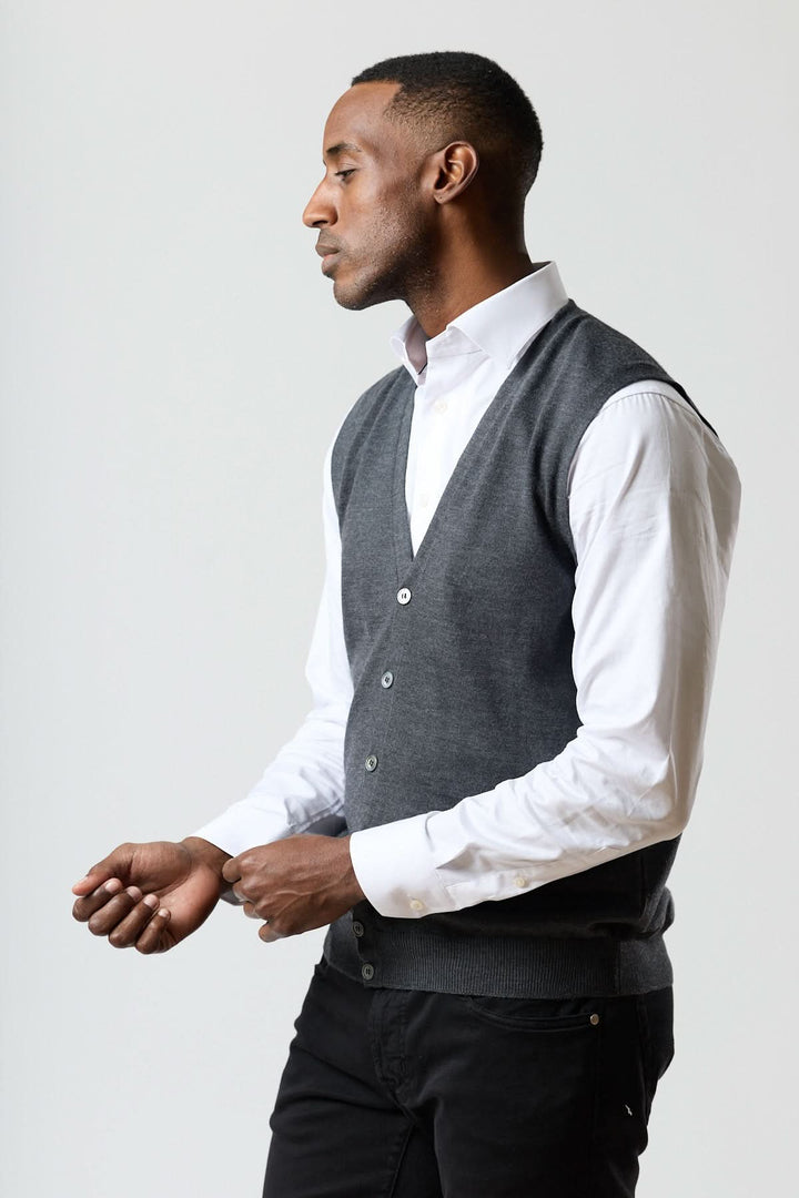 Homme portant un gilet en laine mérinos à col en V élégant, sans manches, gris anthracite, sur une chemise blanche pour un look raffiné.