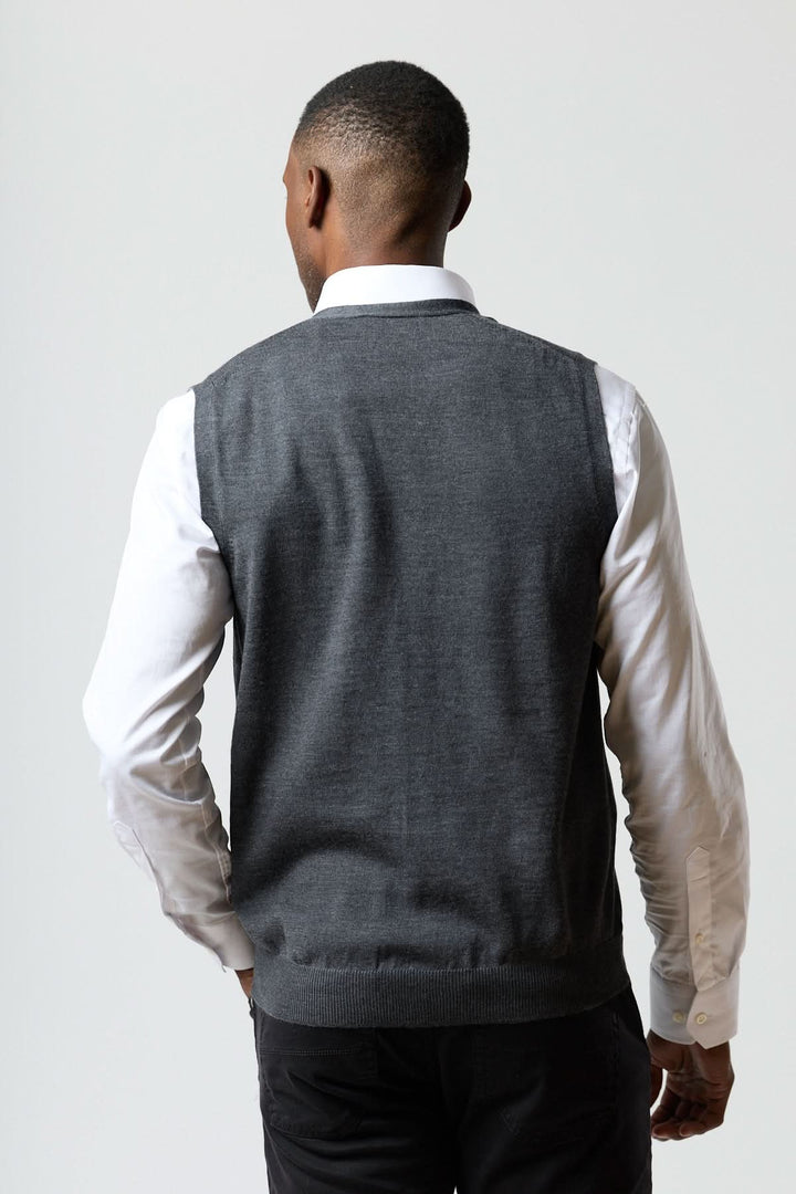 Homme portant un gilet en laine mérinos à col en V de couleur grise, vu de dos, confort et élégance italienne décrits en français.