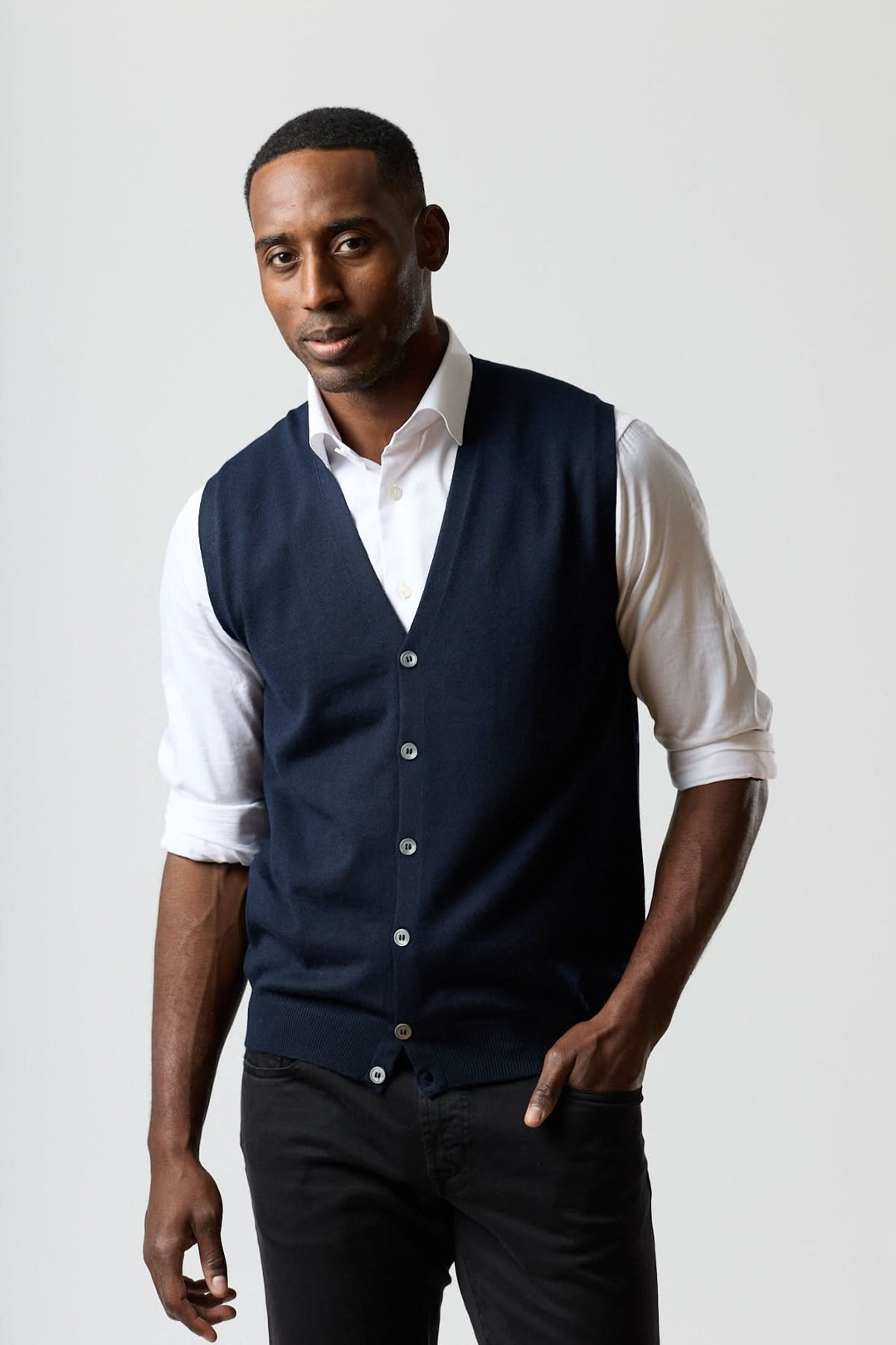 Homme portant un gilet en laine mérinos à col en V, élégant et ajusté, sur une chemise blanche pour un look raffiné.
