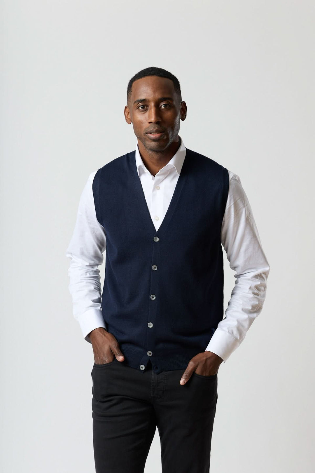 Gilet en laine mérinos à col en V porté sur une chemise blanche, confection italienne raffinée, coupe ajustée moderne.