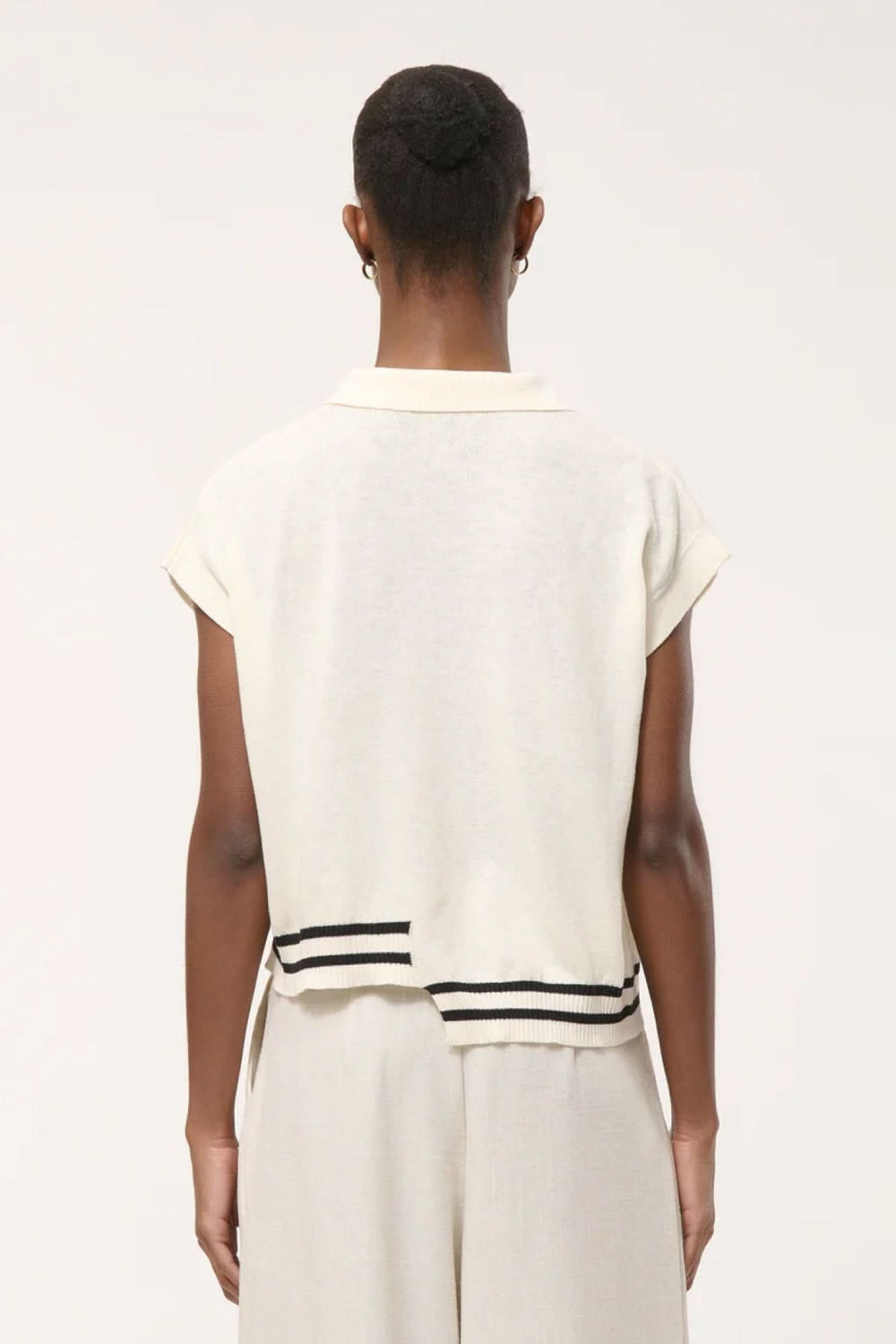 Dos du Haut en tricot à rayures contrastantes avec col polo ouvert et rayures à l'ourlet, porté avec un pantalon ample beige.