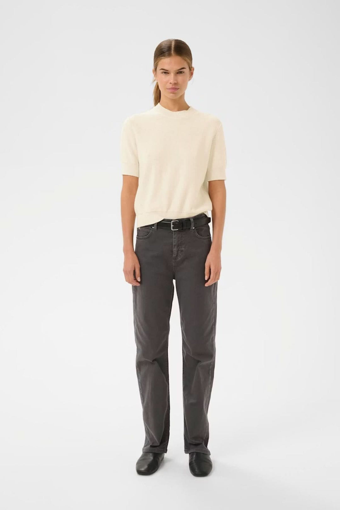 Modèle portant un Haut à manches courtes NAASU en maille beige avec coupe droite et encolure arrondie, style épuré et élégant.