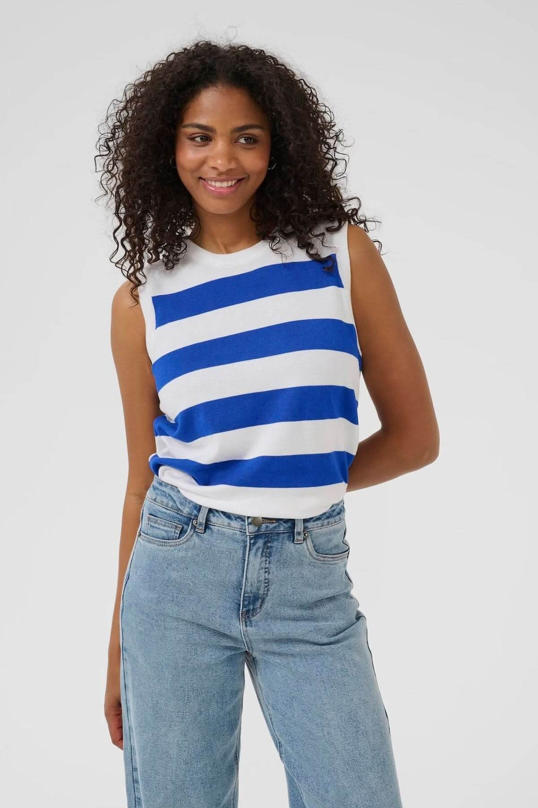 Haut sans manches rayé bleu et blanc porté avec un jean, idéal pour un look estival décontracté.