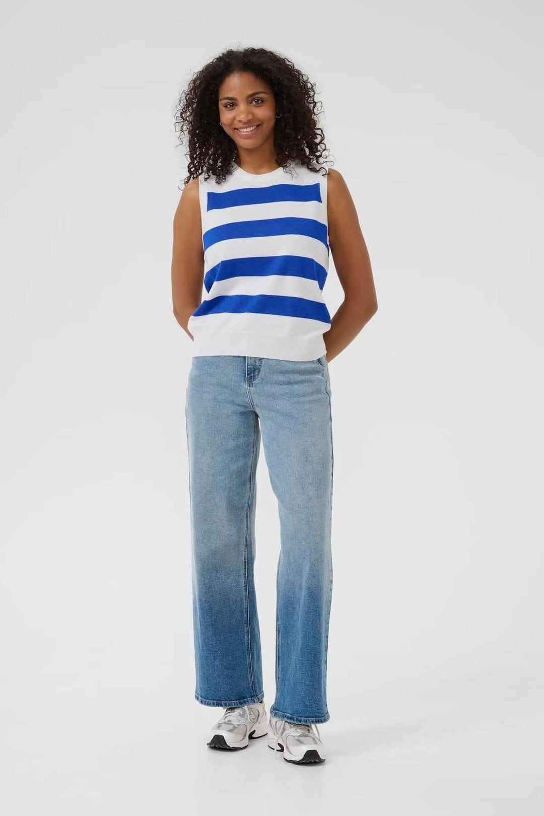 Haut sans manches à rayures bleues et blanches, porté avec un jeans clair, idéal pour un look estival décontracté.