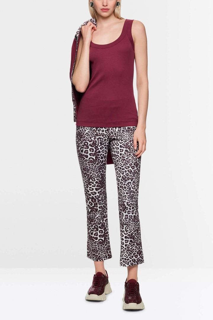 Femme portant un haut sans manches en coton côtelé bordeaux, avec un pantalon imprimé léopard, posant pour une photo de mode.
