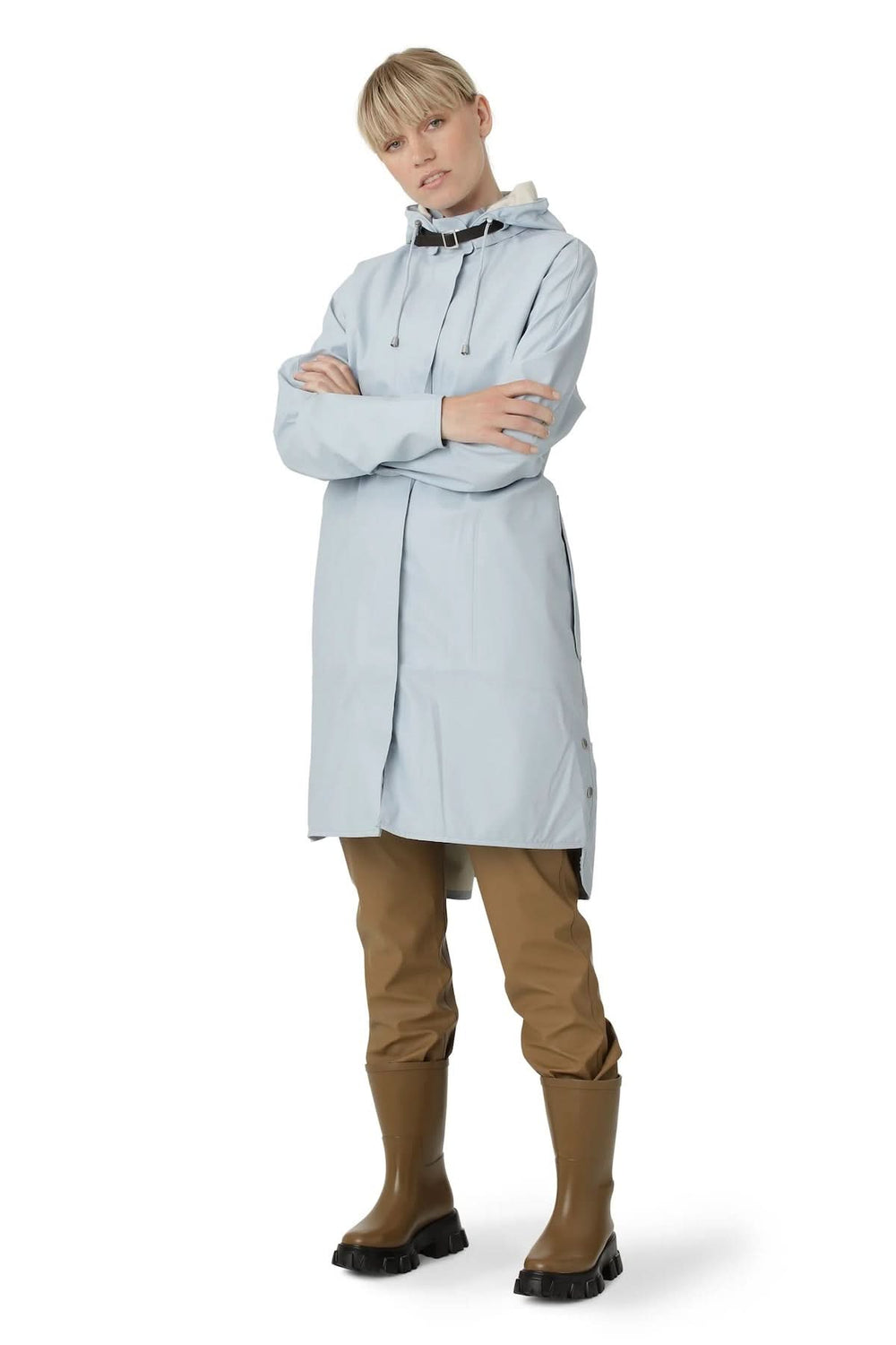 Manteau imperméable léger avec capuche, porté avec pantalon cargo et bottines, style moderne et fonctionnel.