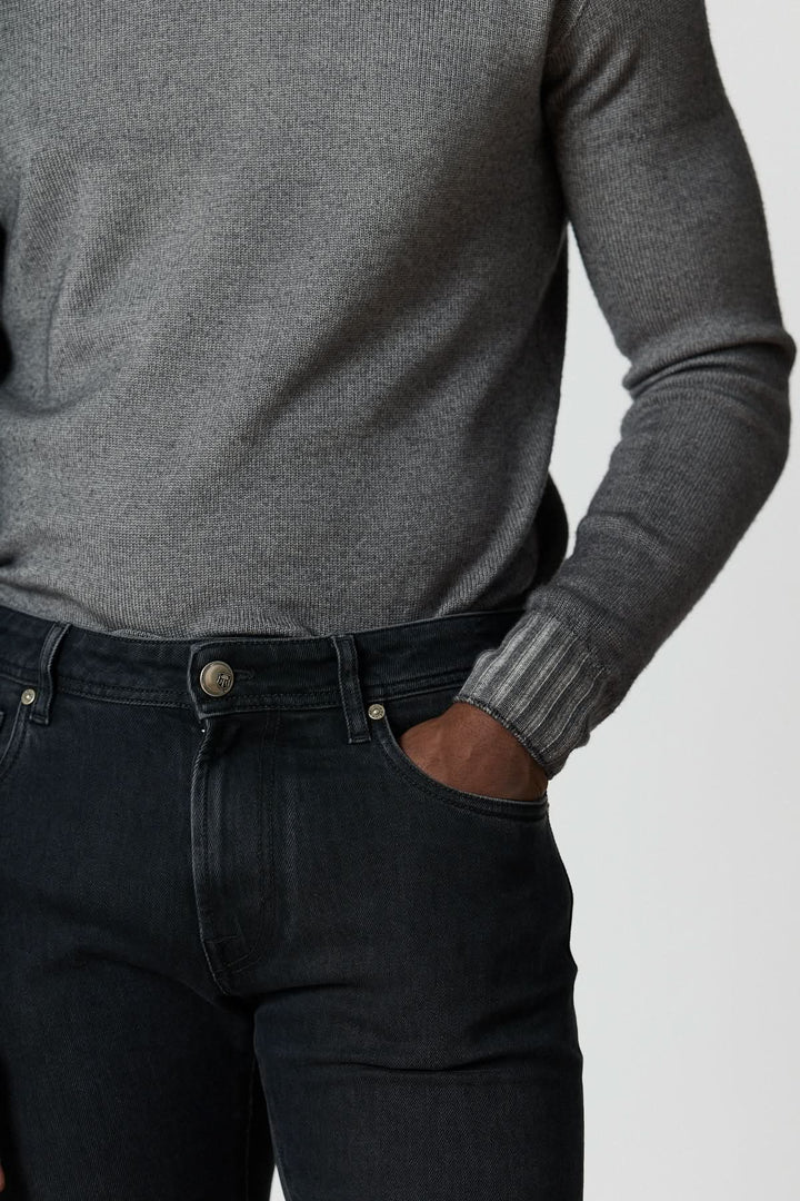 Jean 5 poches en denim stretch gris foncé ajusté pour un look moderne et confortable, porté avec un pull gris.