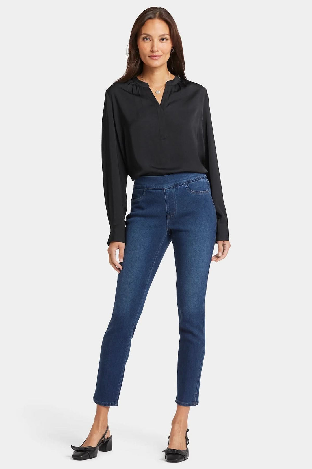 Femme élégante portant le jean skinny à enfiler Alina avec une blouse noire.
