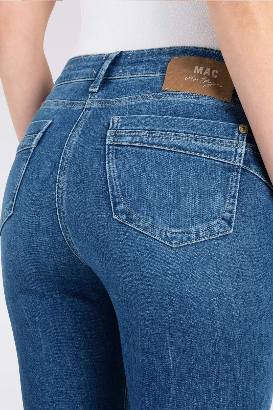 Jean slim en denim bleu avec poches arrondies et taille basse, offrant une silhouette flatteuse.