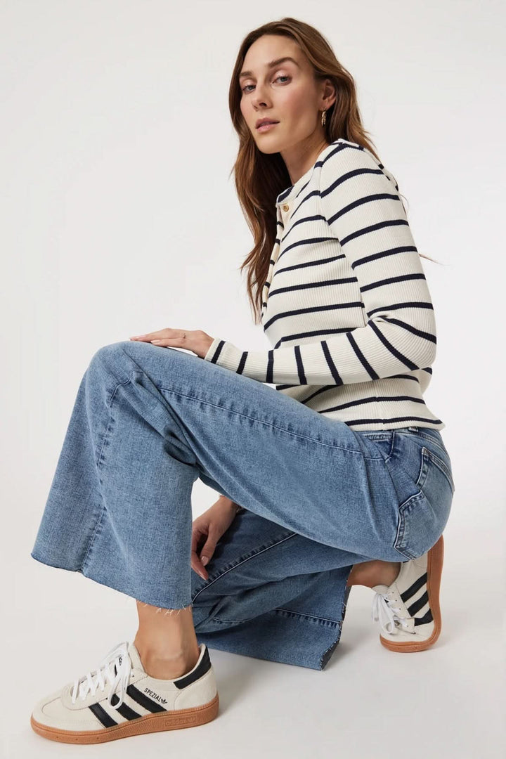 Femme portant Jean Paloma jambe large taille régulière avec un haut rayé et des baskets blanches, style décontracté.