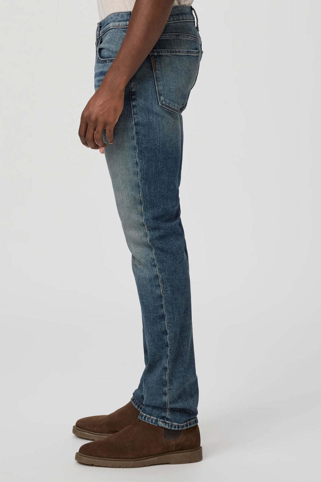 Jean ajusté slim fit avec délavé vintage, offrant confort et liberté de mouvement, porté avec des chaussures marron.
