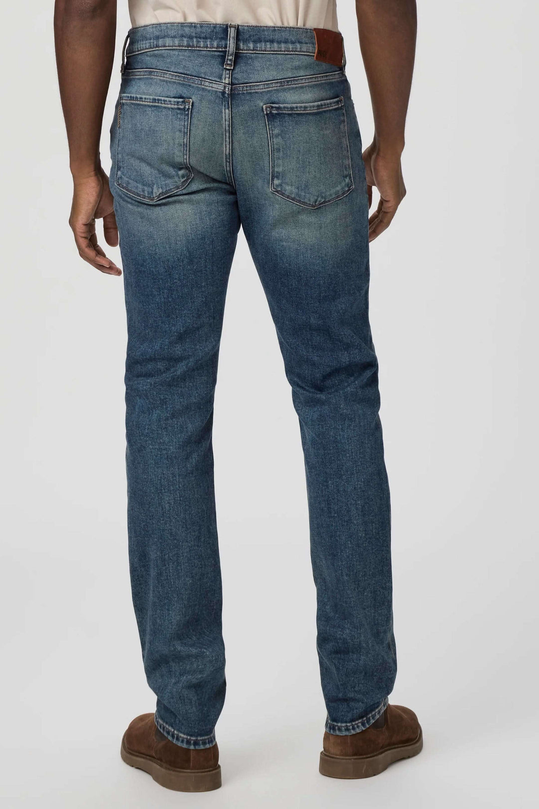 Jean ajusté au style slim fit, délavé vintage, avec détails en cuivre, vue arrière sur mannequin.