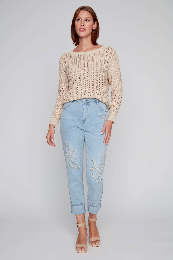 Jean à jambe droite avec broderies florales, porté avec un pull crème, parfait pour un look estival.