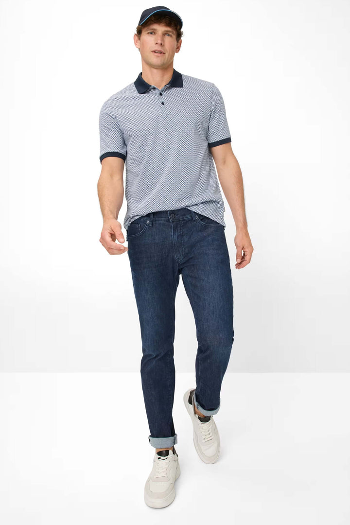 Homme marchant en jean bleu et polo moderne, avec casquette, style décontracté et soigné.