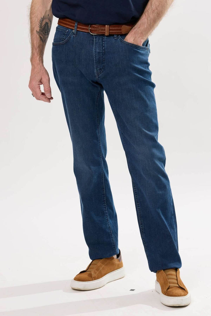 Jean classique homme en denim extensible, coupe droite, porté avec des chaussures confortables.