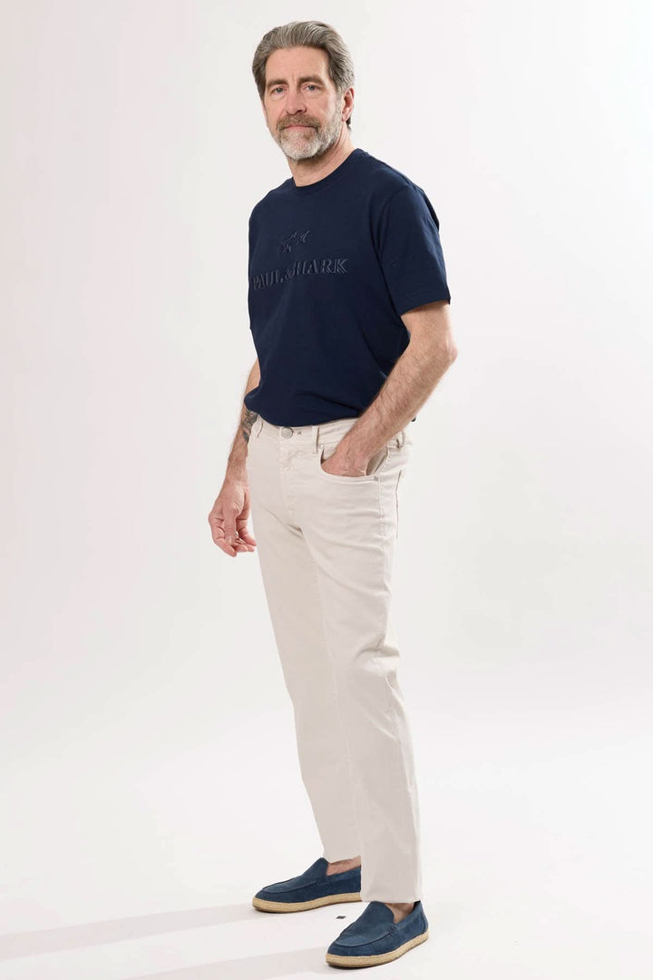 Homme portant un t-shirt marine et un jean coupe ajustée beige, look moderne et décontracté.