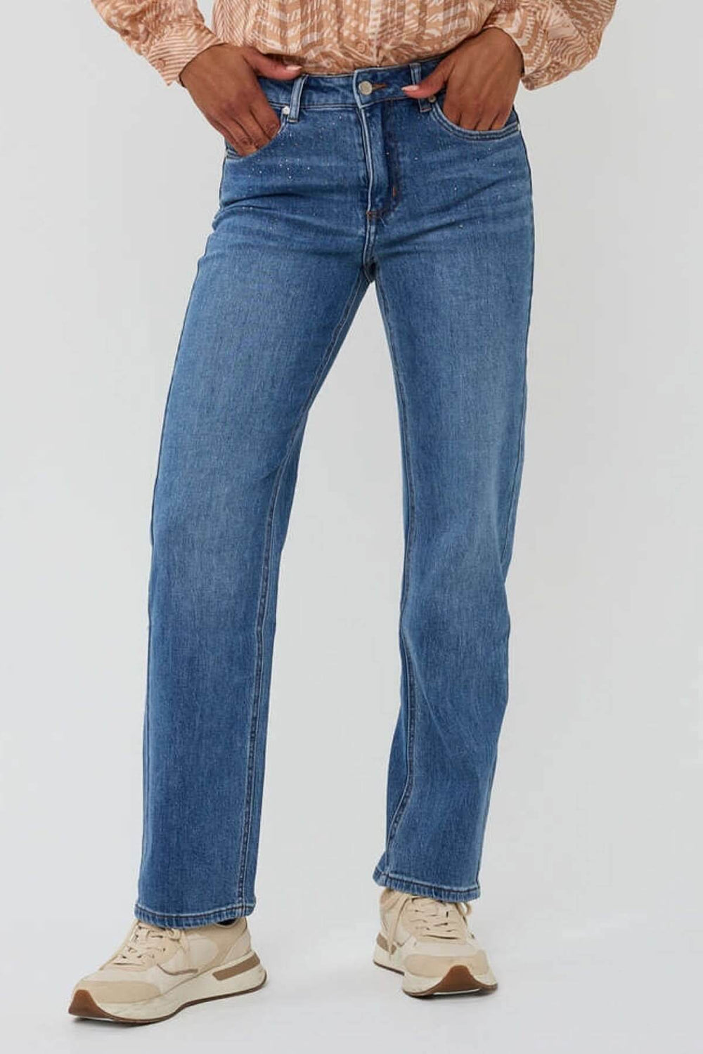 Jean à coupe droite en denim bleu, avec détails scintillants, porté avec un haut stylé.
