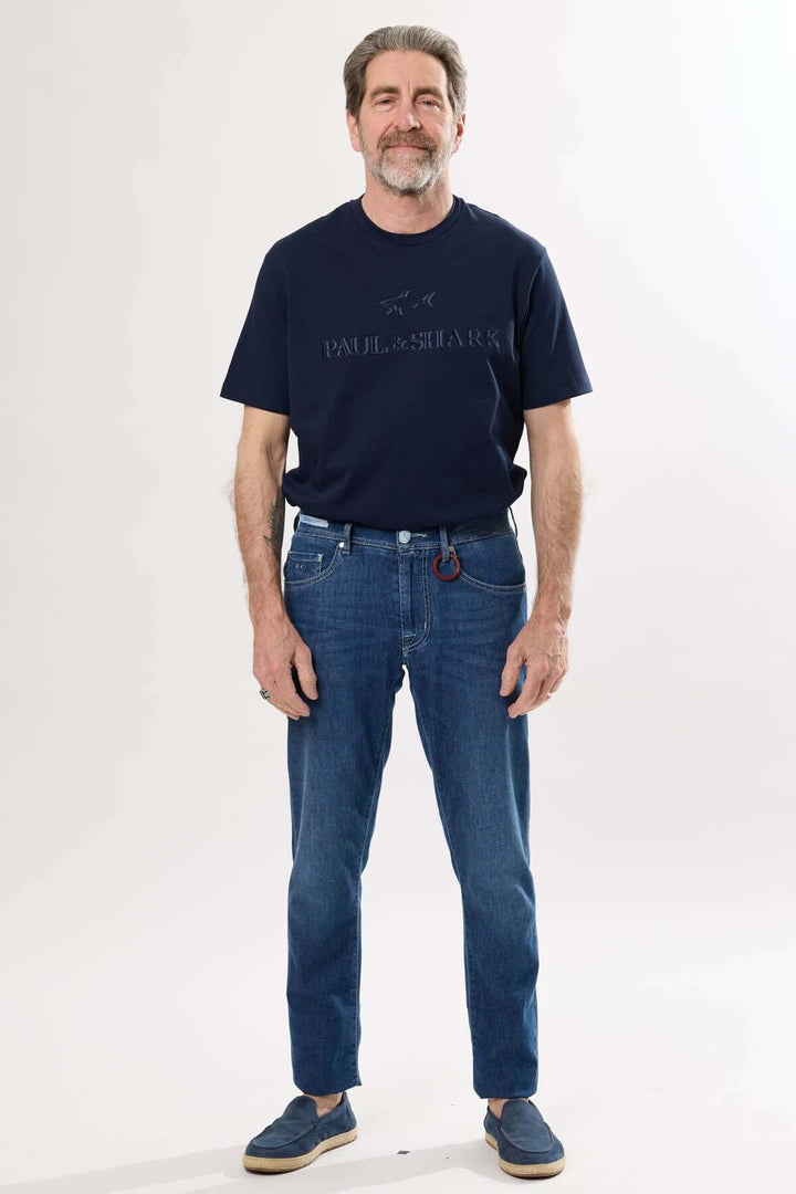 Homme portant un t-shirt bleu marine et un jean coupe droite délavé, style décontracté.