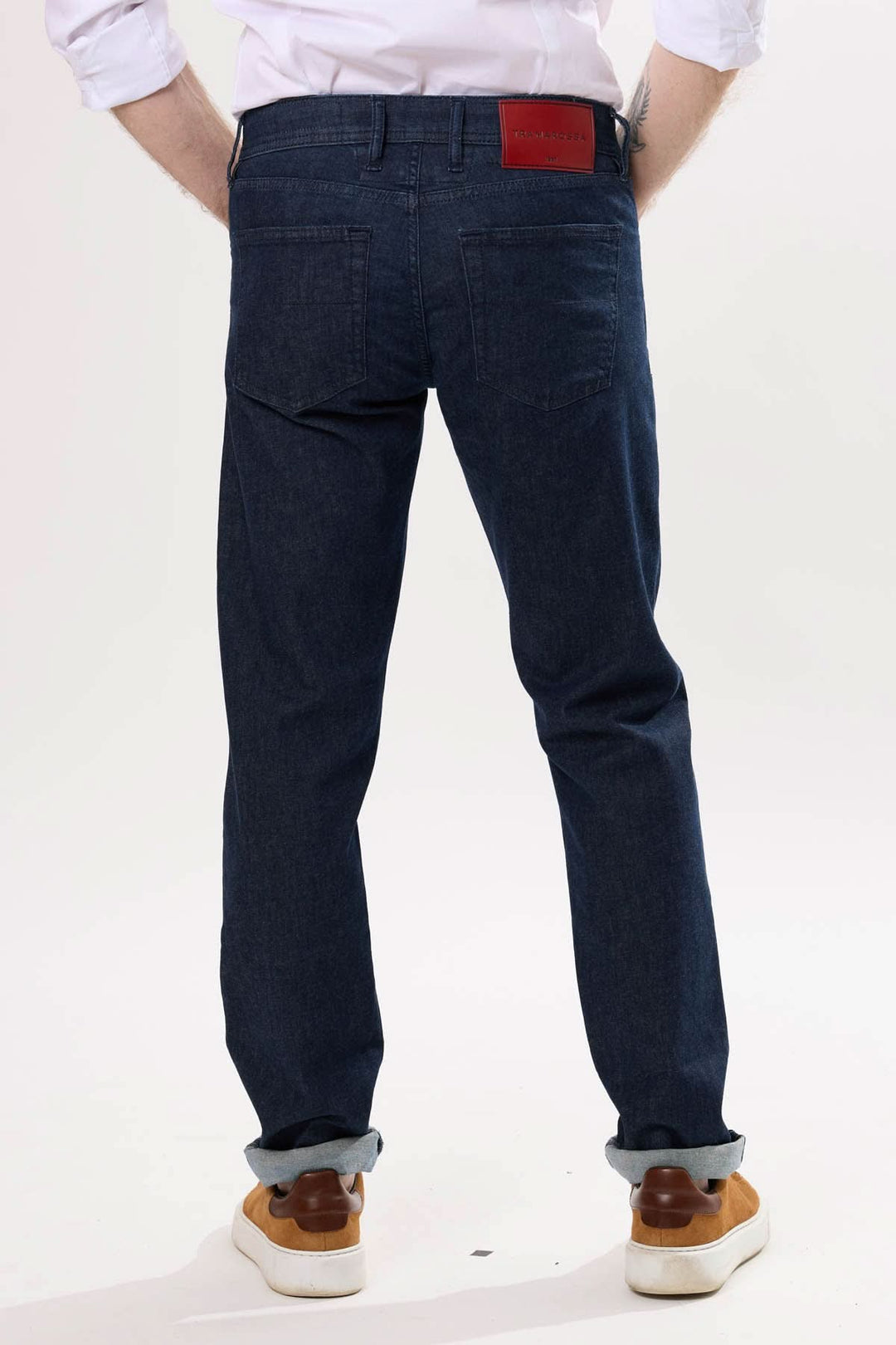 Jean coupe droite avec finition brut, vue arrière, porté avec des chaussures beige.