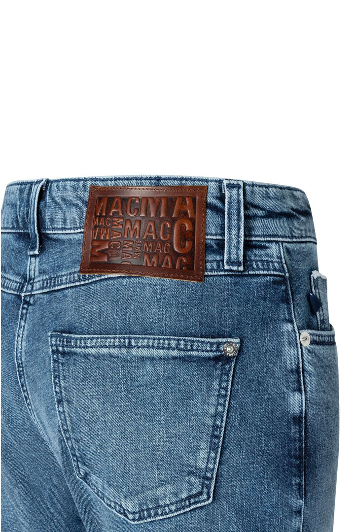 Jean droit avec étiquette en cuir marron, détail du dos et poches, délavage subtil.