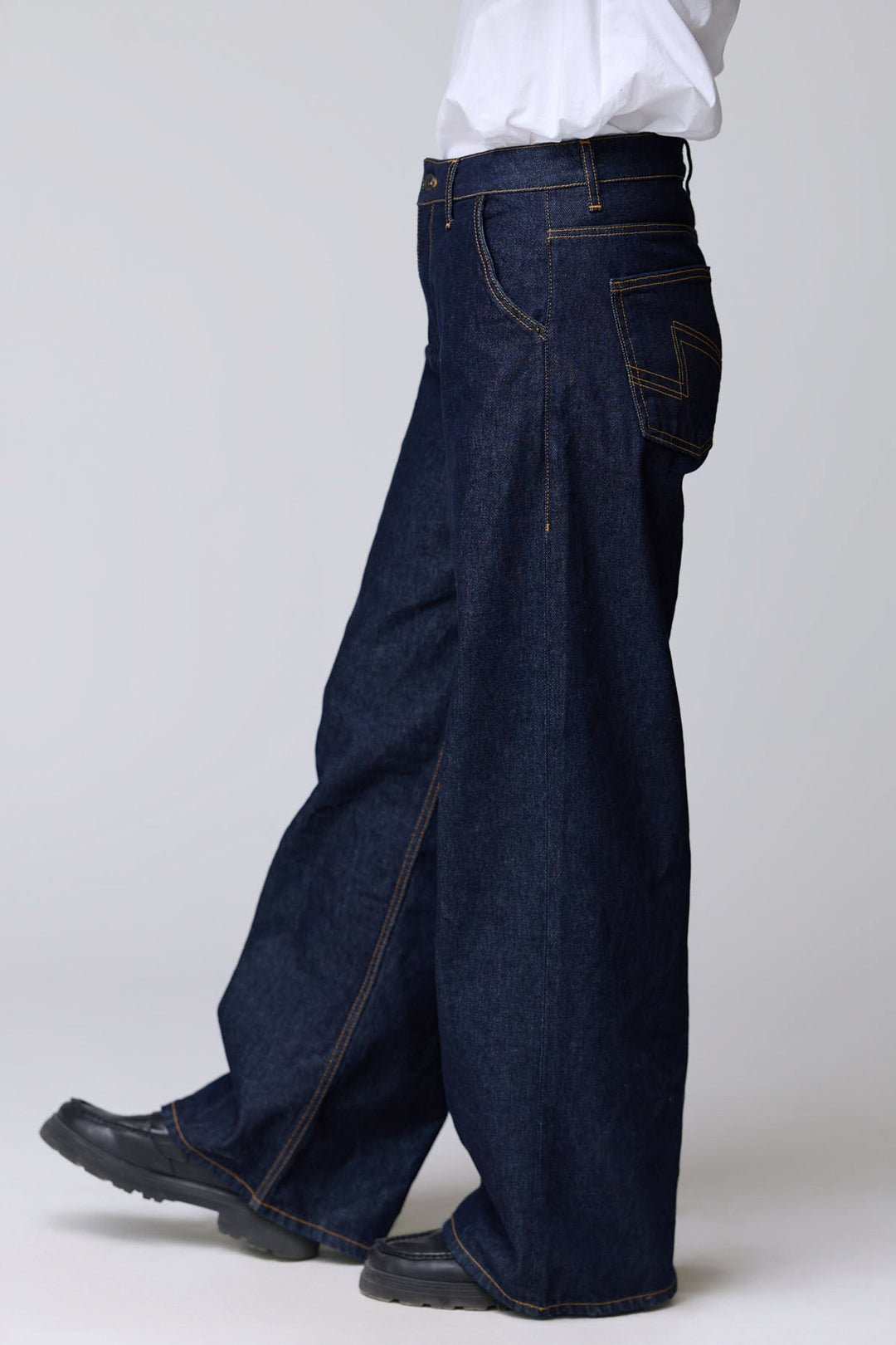 Jean à jambe large style décontracté en denim épais avec surpiqûres contrastantes et coupe ample, vue latérale.