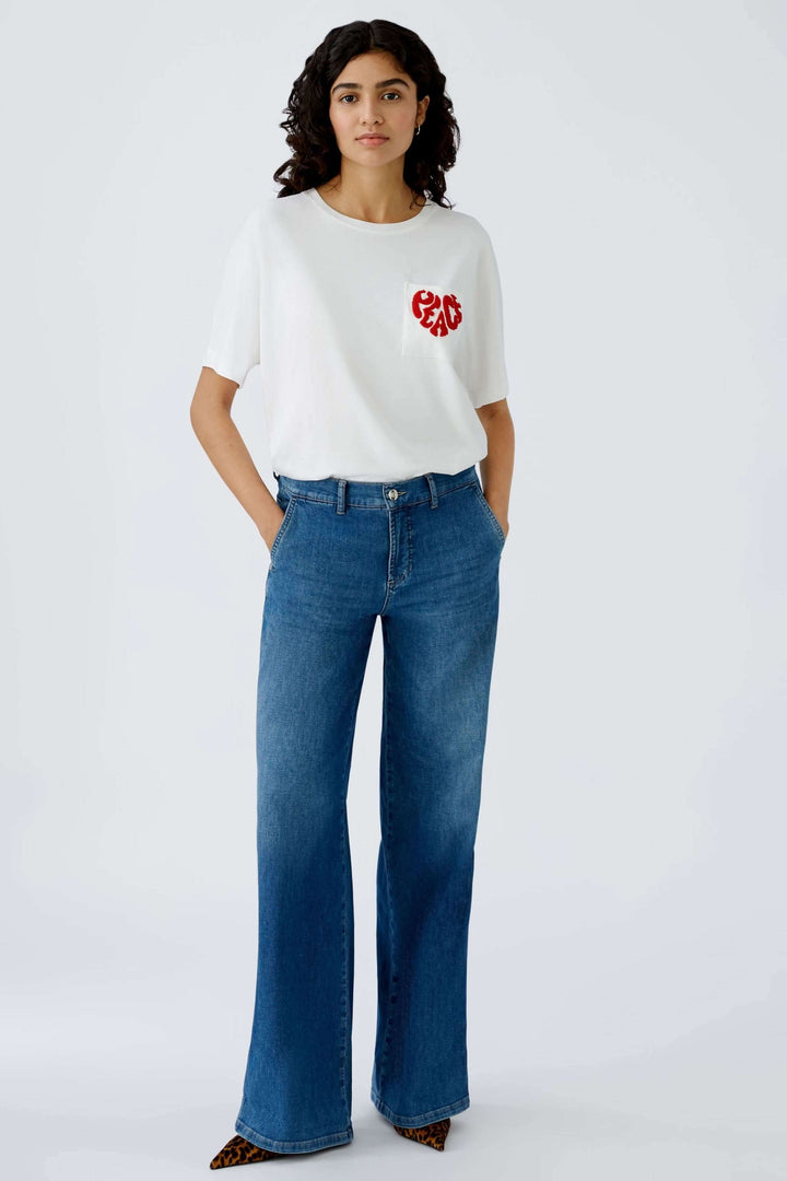 Jean à jambe large en denim avec un t-shirt blanc, offrant une silhouette moderne et décontractée.